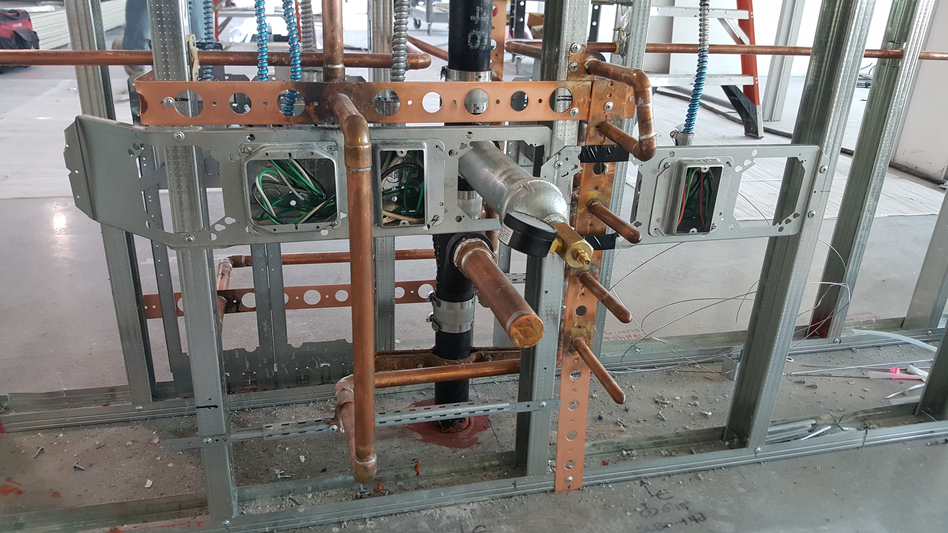 Multi-station rough-in with cleanouts and copper branch lines on steel studs.