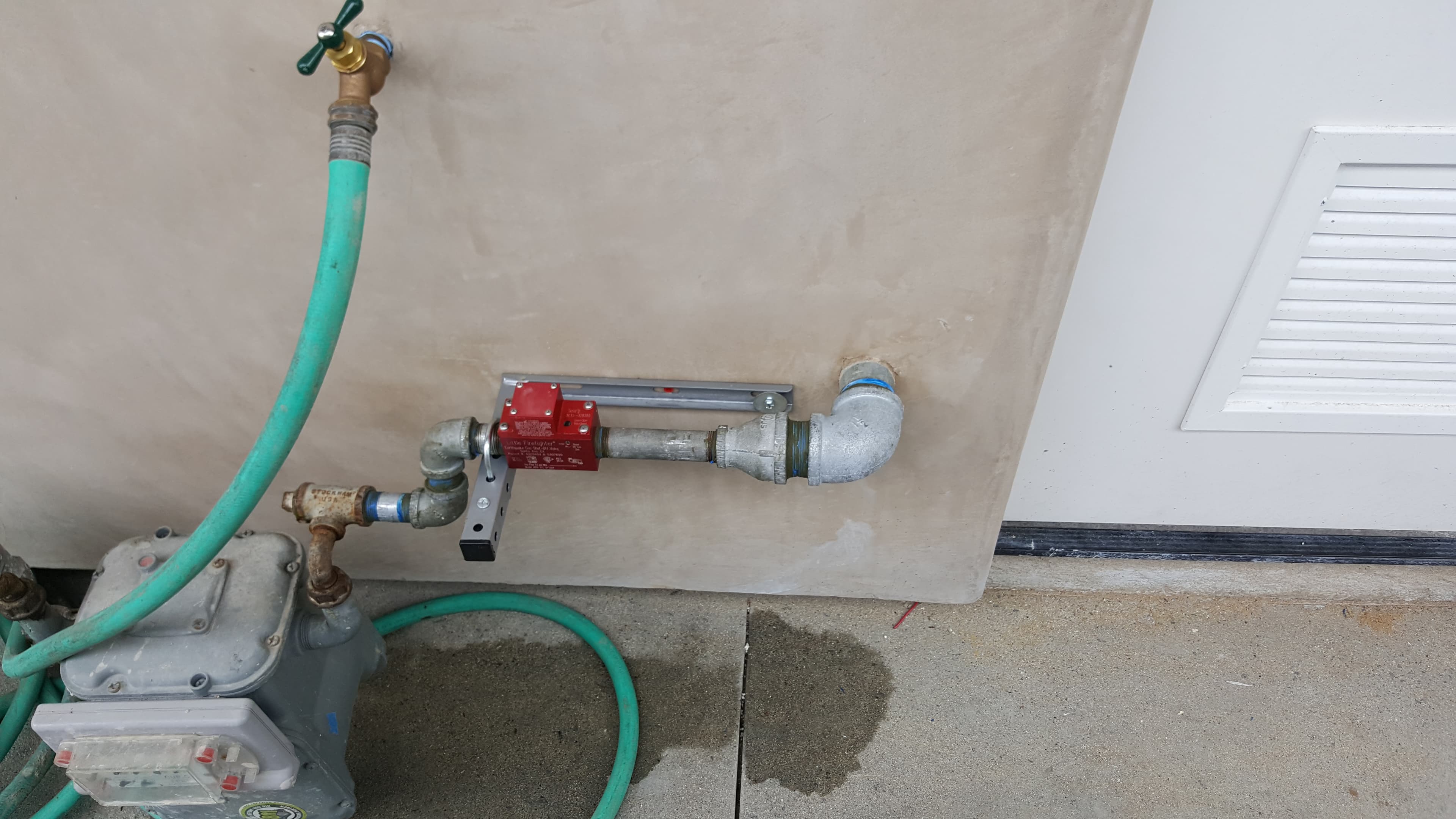 Exterior gas line with seismic shutoff valve and rigid support.