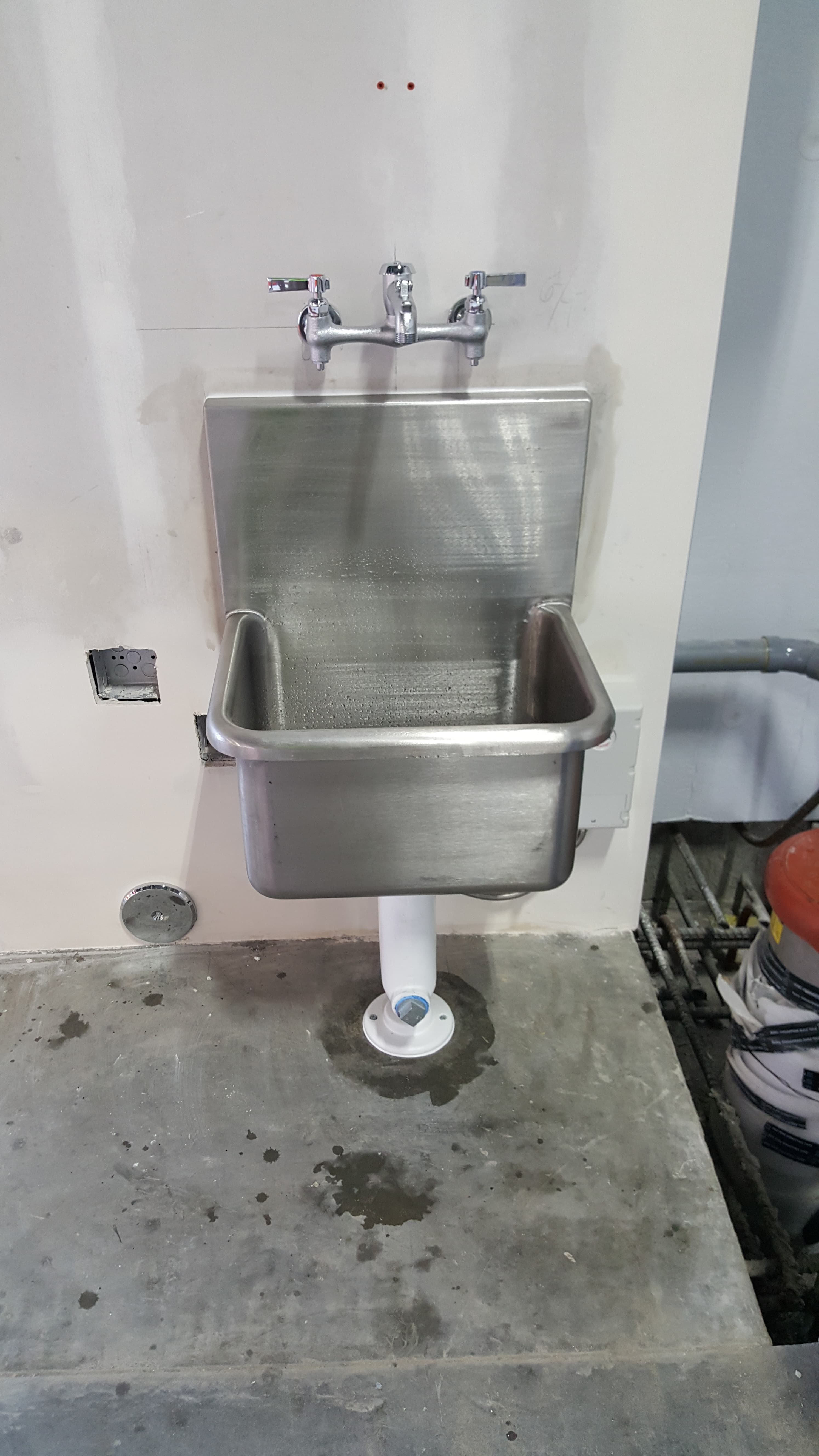 Wall-mounted mop sink with trap and backflow protection.