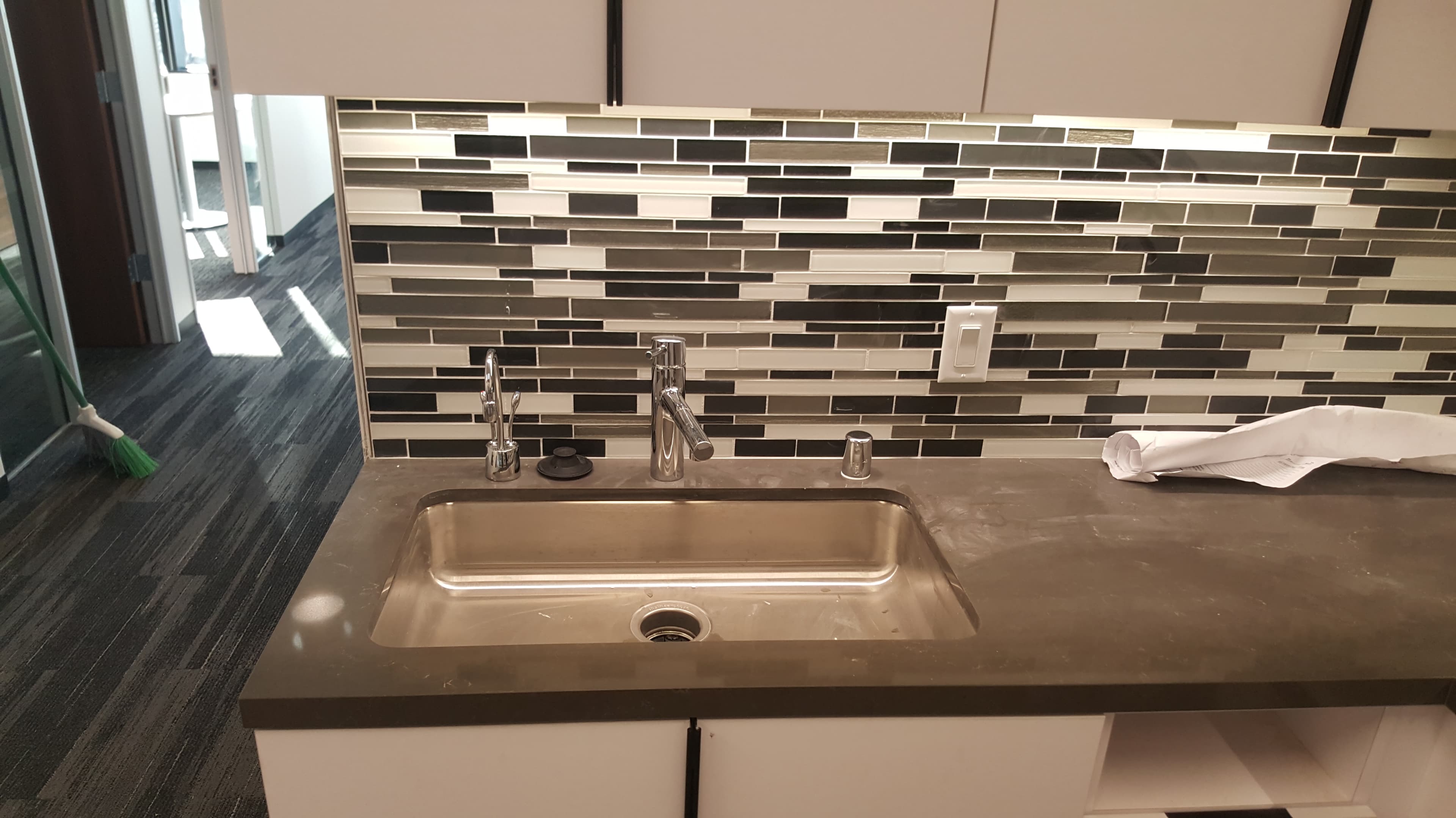 Breakroom sink with filtration/soap dispenser and tiled backsplash.