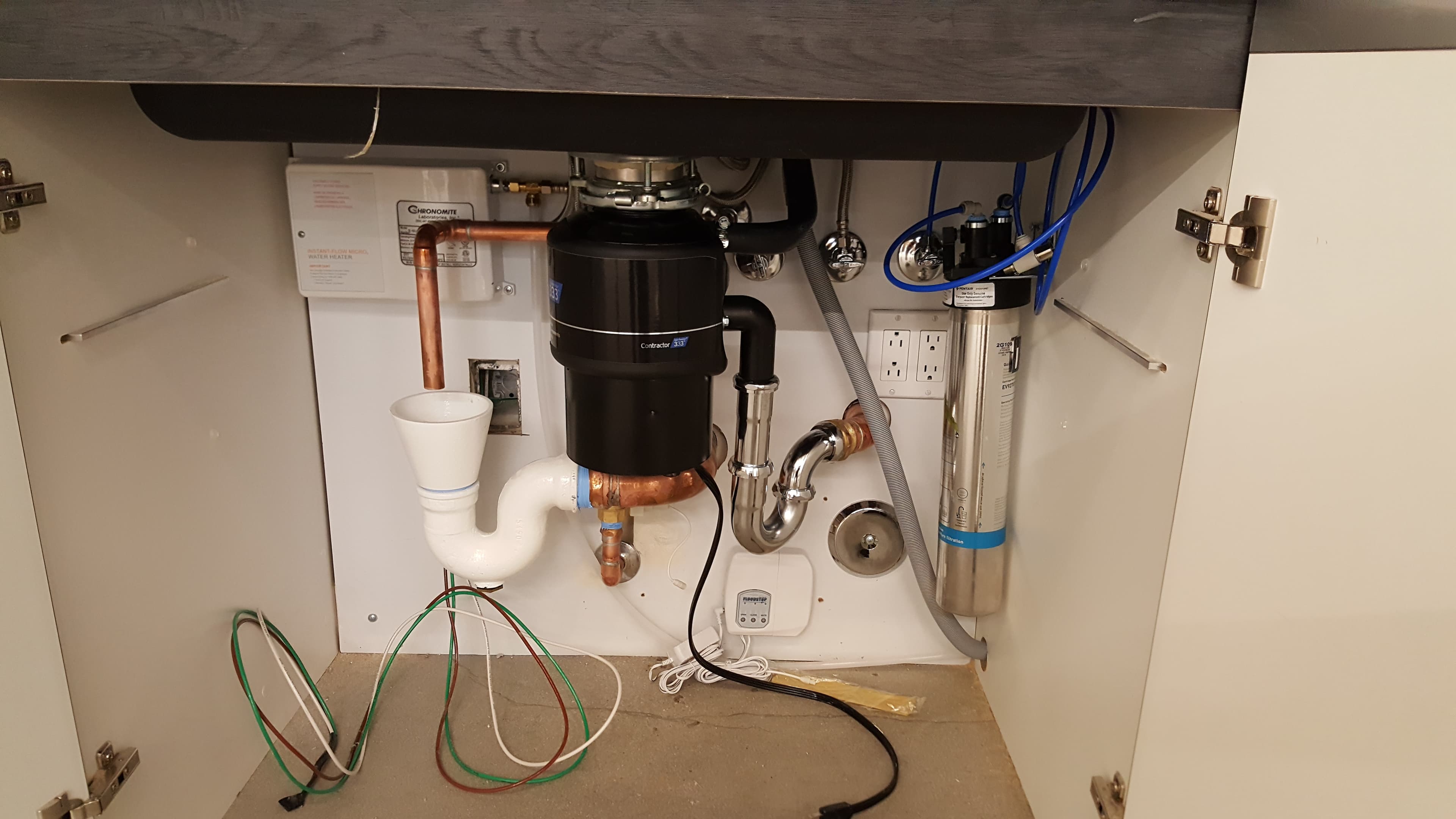 Under-sink disposal, trap, shutoffs, and water filtration canister in a commercial breakroom.